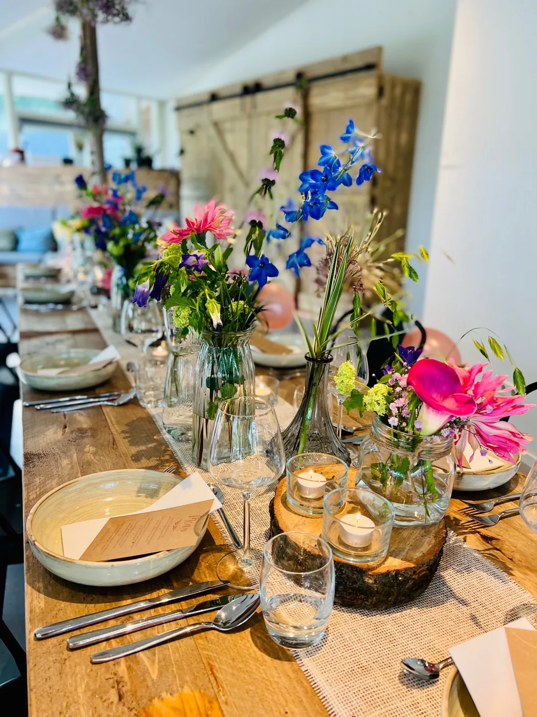 Sfeervol gedekte houten tafel met kleurrijke bloemen en kaarslicht