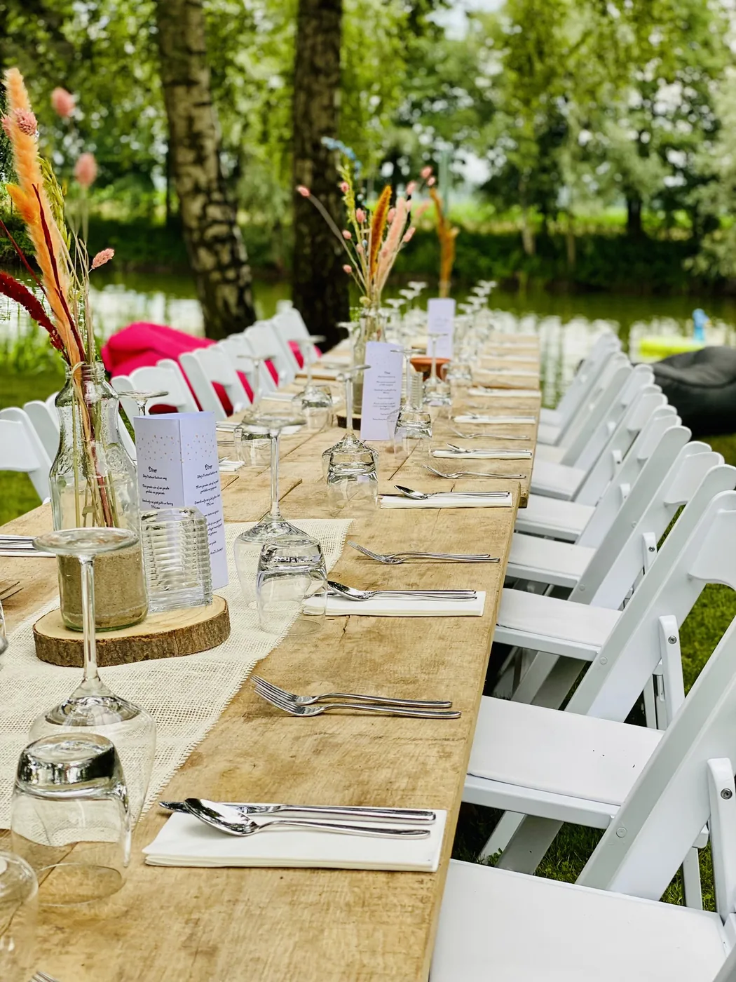 Lange houten dinertafel in een groene tuin aan het water